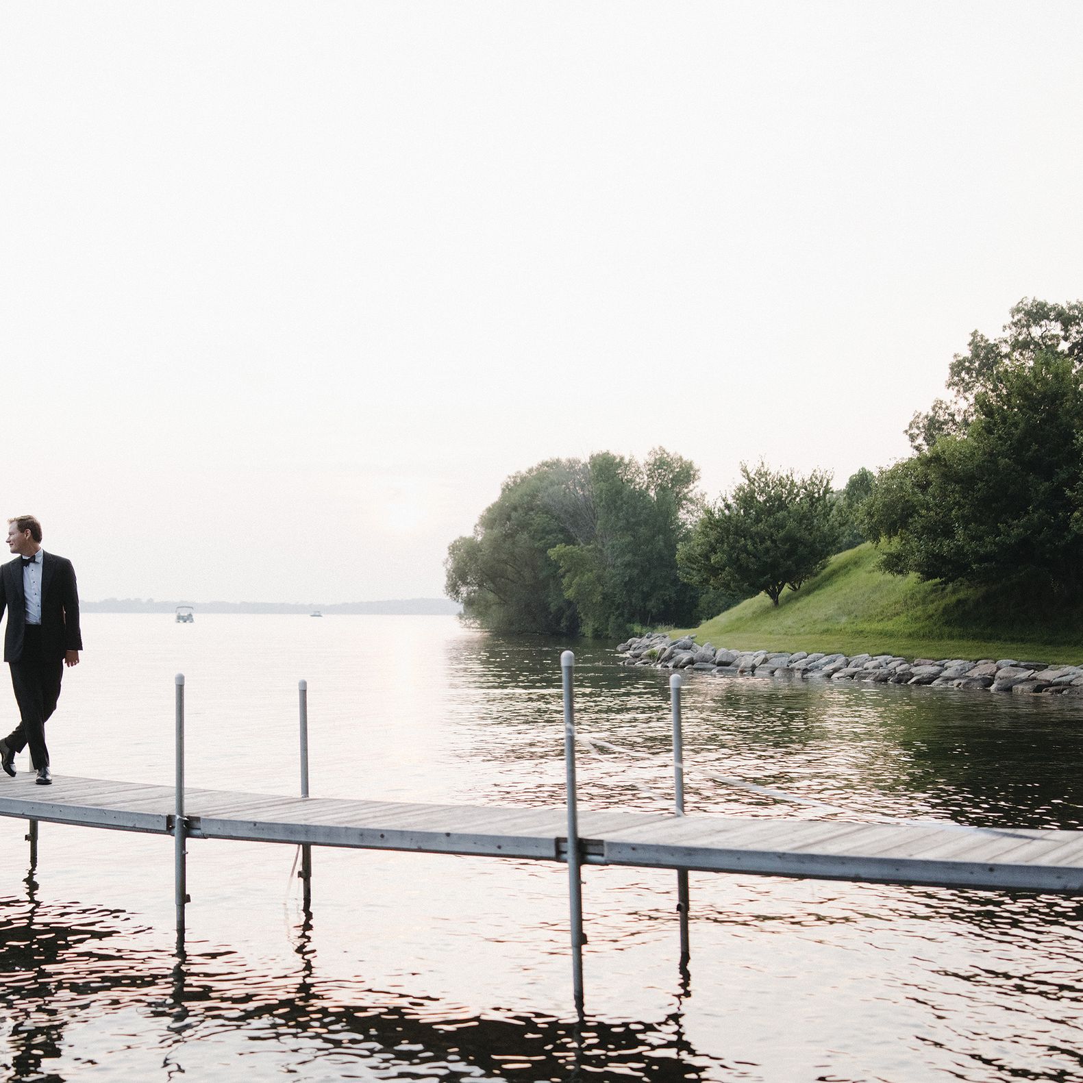 Abby and Jack walk on a dock on their lakeside wedding day at a private residence