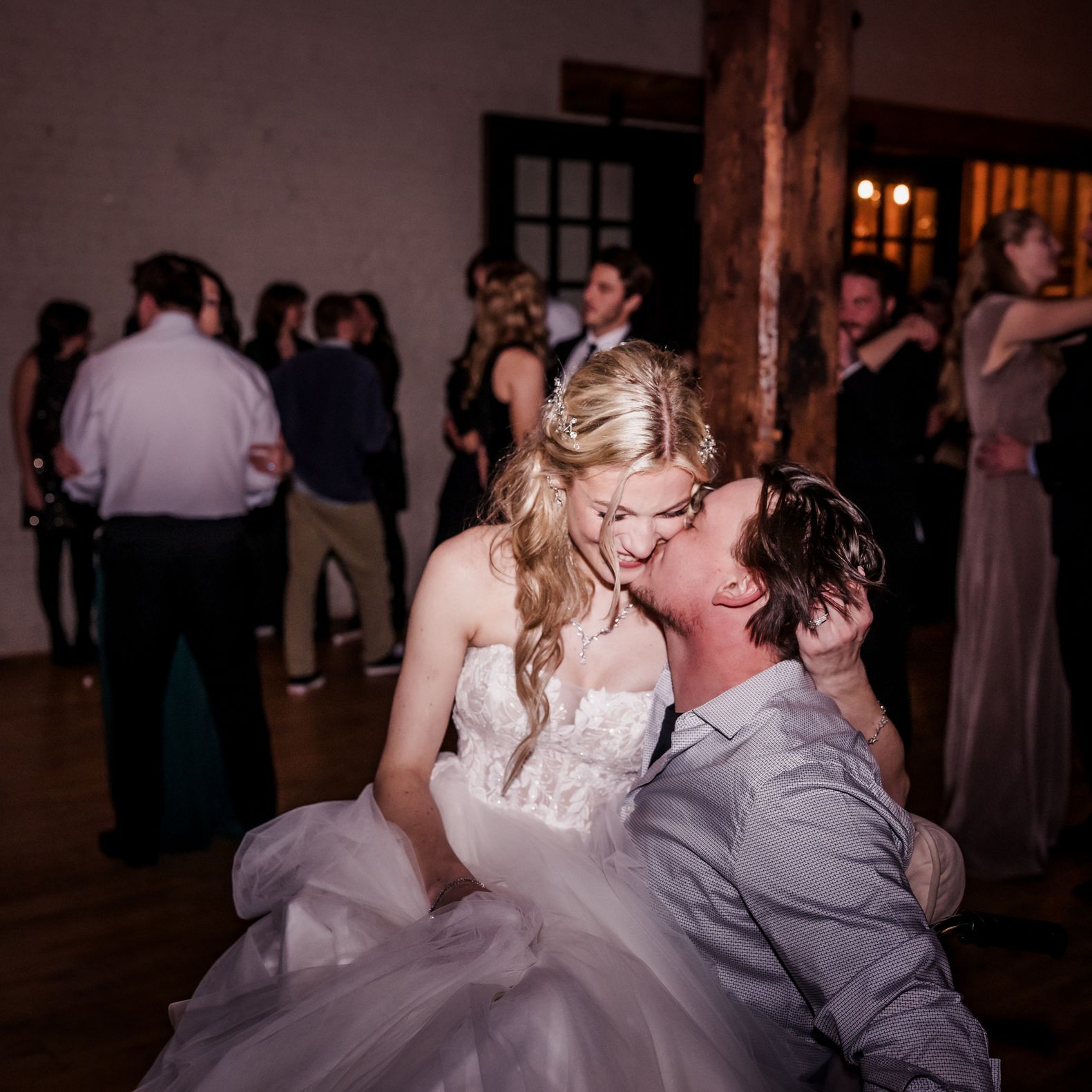 Elizabeth sits on Matthew's lap as they share a kiss on their rustic wedding day at The Lageret