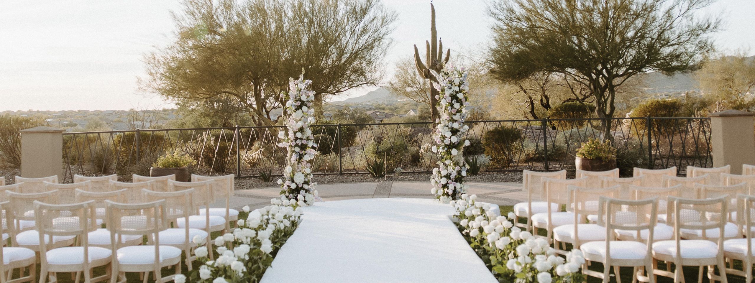 Ceremony space looking over Peoria's native plants, white roses lining the aisle