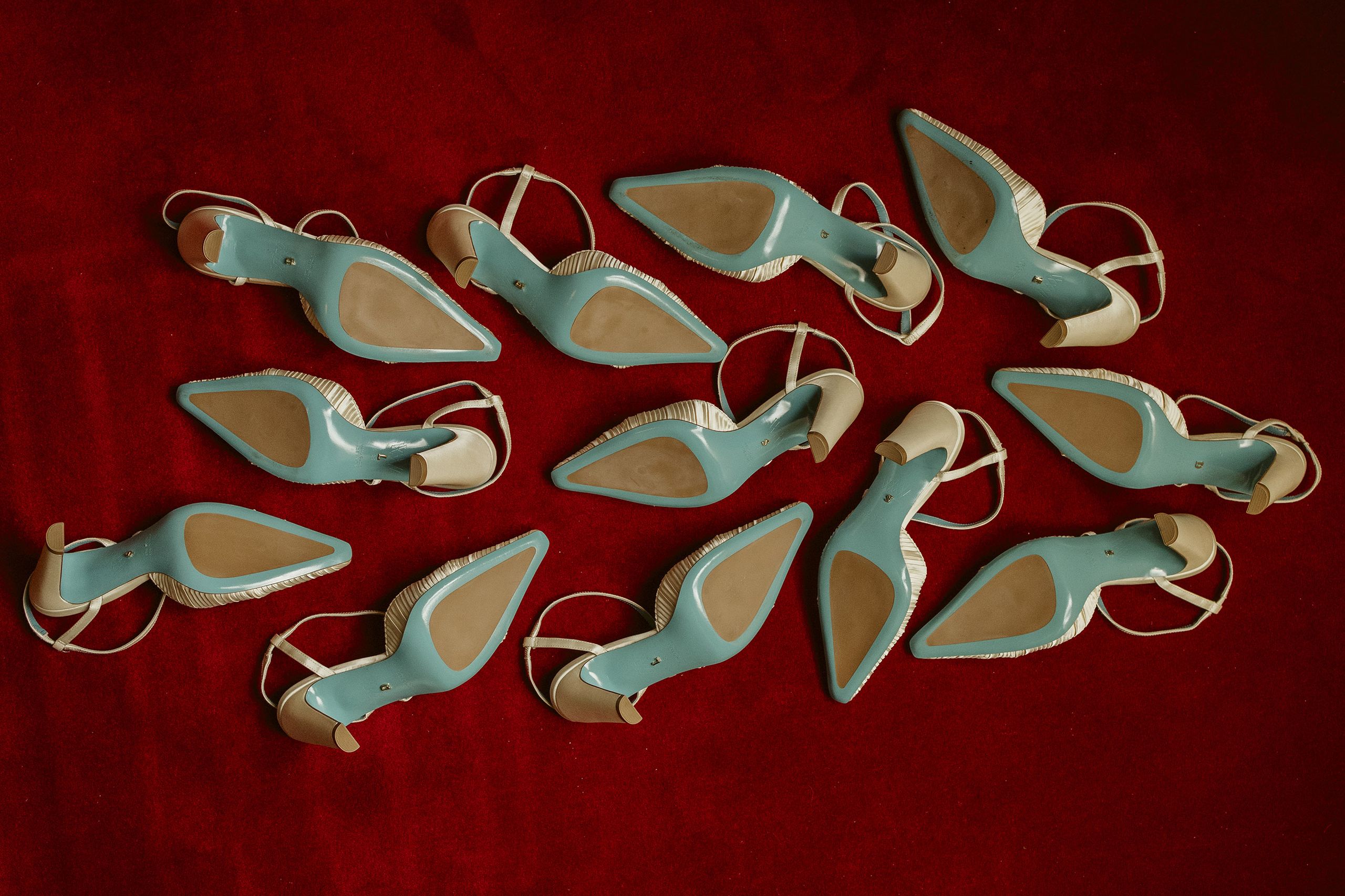 Six pairs of Valentina Rangoni designed shoes, soles up on a red carpet 