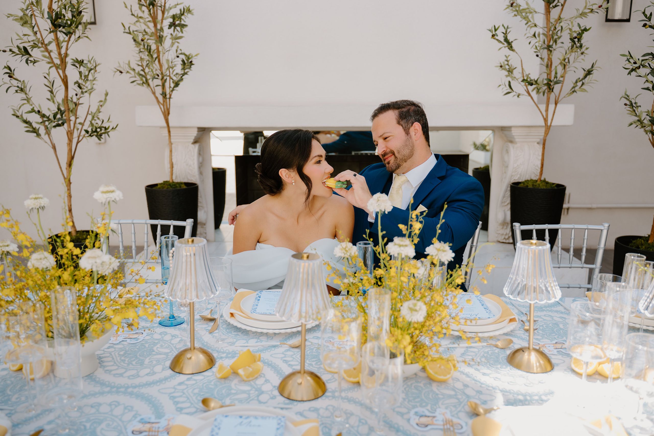 Groom feeds bride a lemon shaped macaron at an Amalfi Coast inspired tablescape 