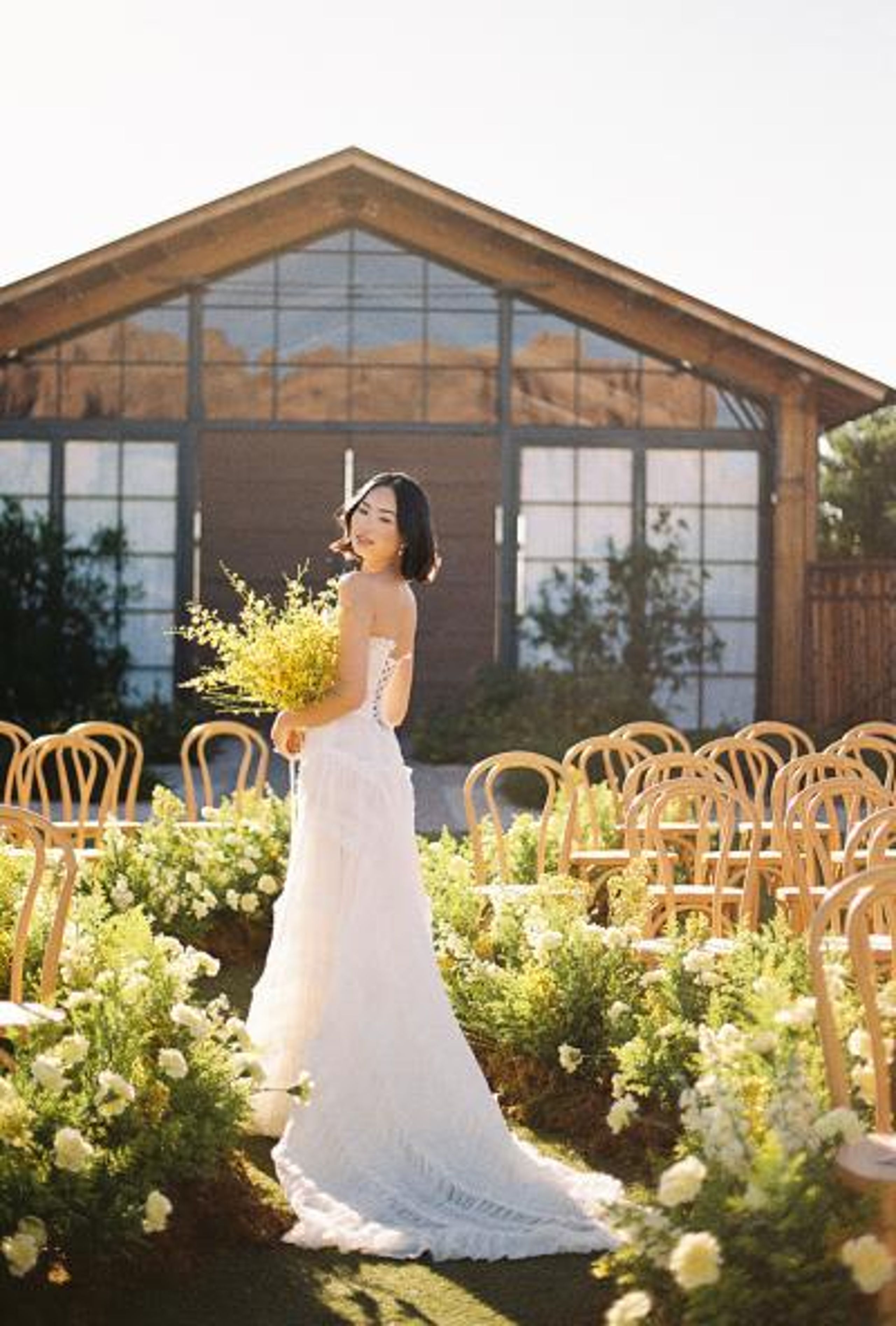 Model poses with yellow bouquet in hand in the middle of a wavy aisle in sunny editorial at the Paseo