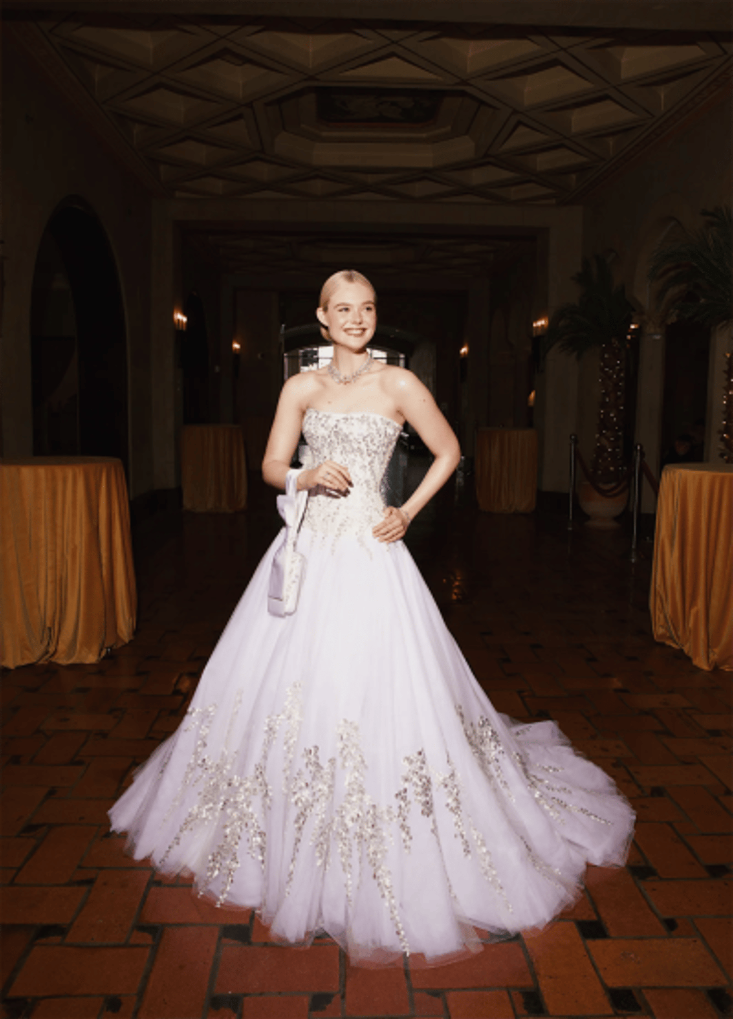 Elle Fanning wearing a white embroidered Givenchy ball gown at the 2026 Oscars red carpet, a bridal-inspired strapless dress with floral embellishments and a full tulle skirt that resembles modern wedding gown trends.