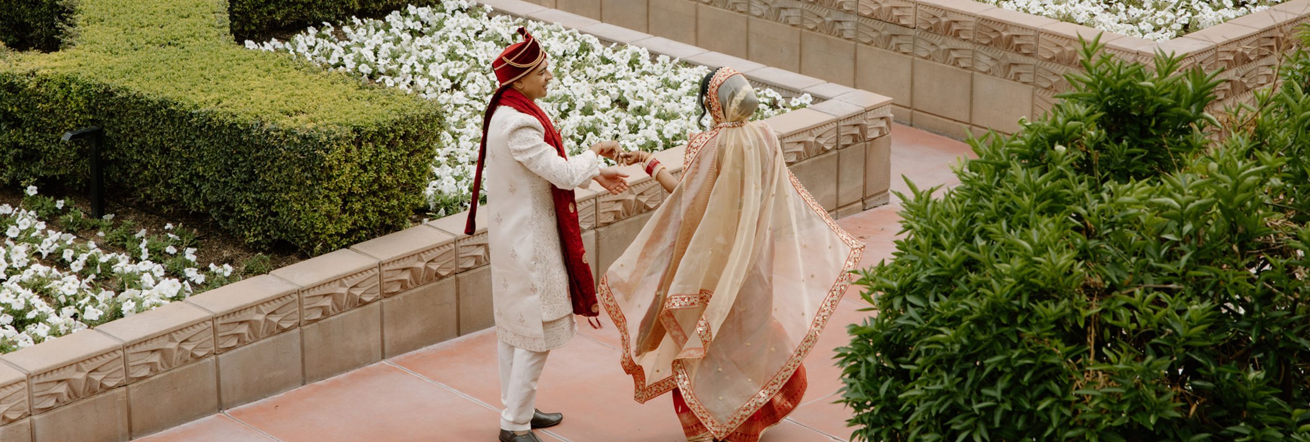 Nikita and Sahil walk hand in hand amidst the courtyard at the Arizona Biltmore on their wedding day