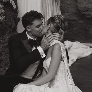 Bride and groom share a kiss sitting at their outdoor altar at Woods & Co.