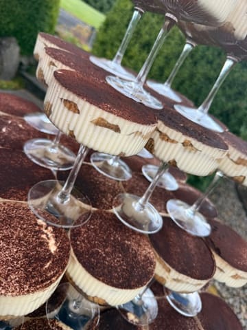 Individual tiramisu-style layered desserts served in stemmed glasses and dusted with cocoa.