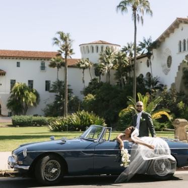 Cristabel and Martin pose in their vintage getaway car outside of the Santa Barbara Courthouse