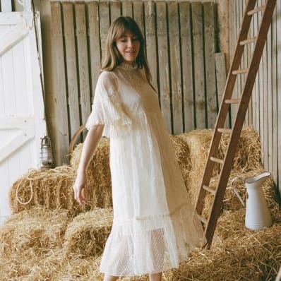 Bride in a barn wearing the Havisham dress by Joanie, a romantic Victorian-inspired wedding gown with polka-dot mesh, lace embroidery, and flounce sleeves