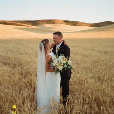 Abbey and Peter pose in golden fields of wheat on their wedding day