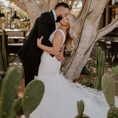 Bride and groom share romantic embrace framed by cacti