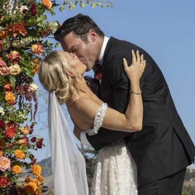 Bride and groom share kiss at the altar with flowers framing them