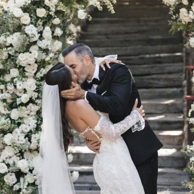 Bride and groom seal their vows with a kiss framed by an arch of lush white florals
