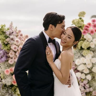 Groom kisses bride's cheek on lush altarspace platform on their wedding day at Montage Laguna Beach