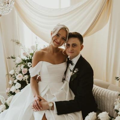 Bride sits on groom's lap in romantic lounge vignette on wedding day at Woodhaven