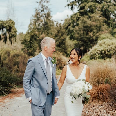 Bride and groom walking holding hands and looking at each other at Seattle Pacific Connections Garden at Washington Park Arboretum