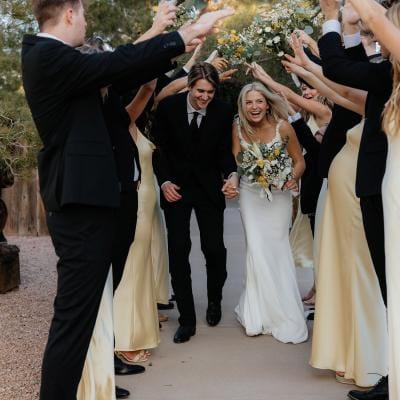 Bride and Groom run under archway created by bridal party
