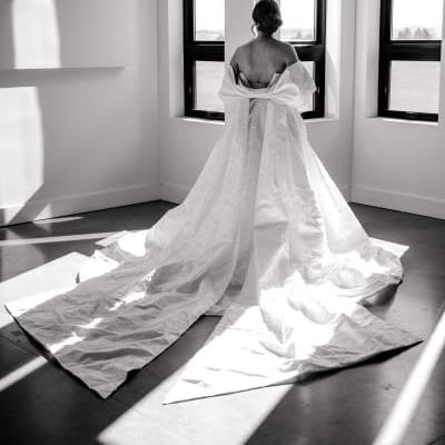 Black and white photo of model wearing gown with bow detail shawl 