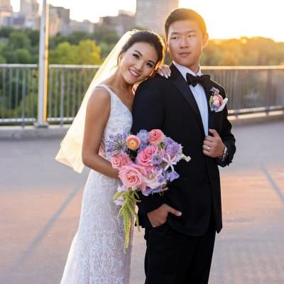 Bride and groom embrace with bright whimsical florals in hand