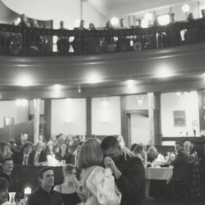 Caitlin and Josh Sharing their First Dance with Friends and Family Watching from the Balcony of The Grand Event Center