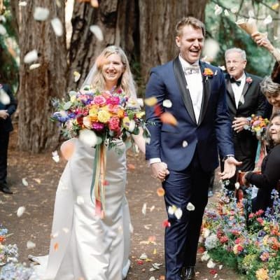 Flower Petals Thrown in the Air while Katie and Sam Walk Down the Aisle at Colorful Santa Lucia Preserve Wedding