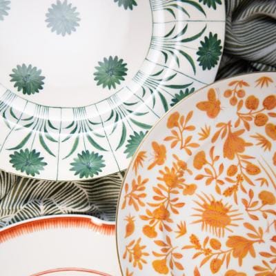 Layered fine china plates from Maison de Carine featuring floral and botanical patterns in coral, green, and orange hues—styled for the 2025 Met Gala
