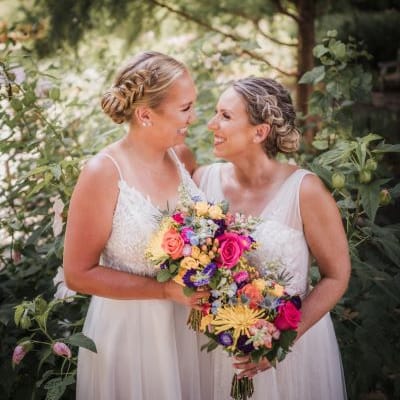Brides stun in coordinating wedding attire amongst lush greenery