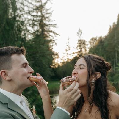 Bride and groom feed each other donuts at outdoor reception
