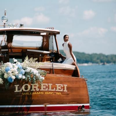 Model poses on a boat decorated in florals floating on Lake Geneva outside of The Abbey Resort
