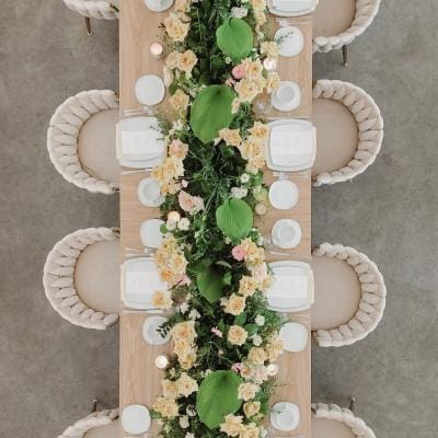 Garden wedding table featuring a long harvest table with lush greenery, soft yellow roses and apricot blooms, styled for summer wedding inspiration at The Hutton House in Minnesota
