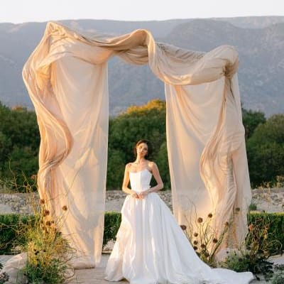 Model poses under architectural and organic altar against mountainous landscape at Topa Vista