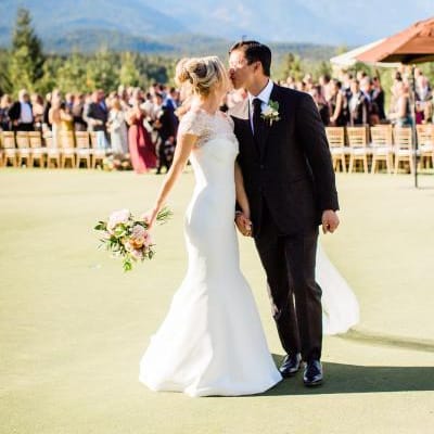 Bride and groom share a kiss after walking down the aisle in outdoor ceremony with mountainous backdrop at Tumble Creek