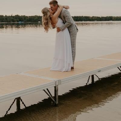 Bride and groom share kiss on a dock with lake in background in lakeside wedding day