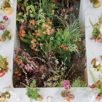 Organic florals in the middle of a rectangular table featuring simple, elegant design in glass house reception space at Woods & Co