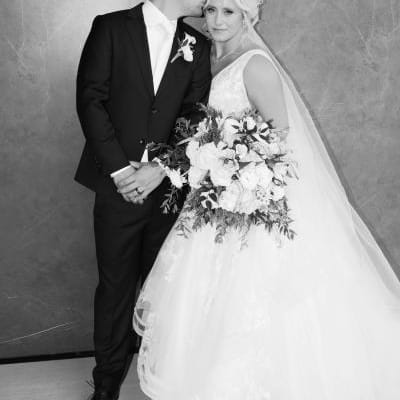 Groom kisses side of bride's head as they pose for their couple portrait outside of Venue 5 Twenty-Two