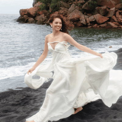 Model poses in fashion-forward wedding gown on the Black Sand Beach with Lake Superior in the background
