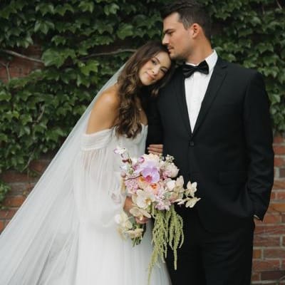 Bride rests her head on groom's shoulder in front of an ivy backdrop at The Bohemian Gardens