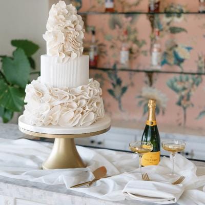 Intricate tiered cake and bottle of champagne in catering editorial at Jeune Perché