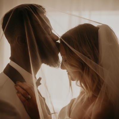 Groom kiss bride's forehead in close up shot in private wedding portrait session
