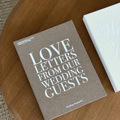 Brown linen keepsake box by The Ceremony Club with "Love Letters from our Wedding Guests" on cover, laying on wooden table