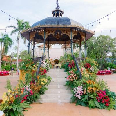 Bright and lush tropical florals line the steps of a gazebo in multicultural wedding in cancun
