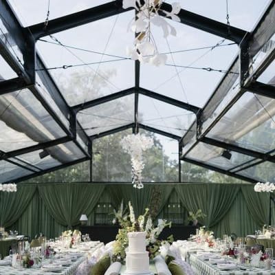 Bold maximalist reception design featuring luxe green draping and textured chandeliers at Woodland Glasshaus