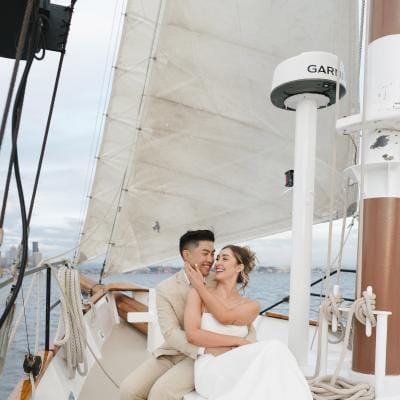 Groom holds bride in his arms on a sailboat for their welcome party