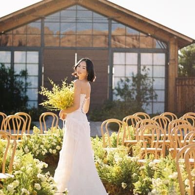 Model poses with yellow bouquet in hand in the middle of a wavy aisle in sunny editorial at the Paseo