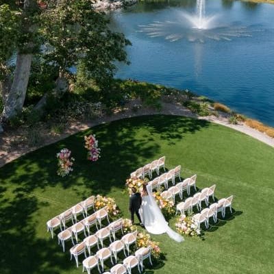 Aerial scene of models walking down aisle in outdoor ceremony featuring peachy florals on the grounds of Monserate Winery