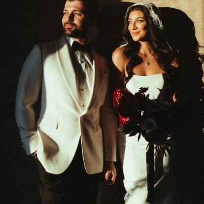 Bride and groom pose against a wall with dramatic shadows cast over them