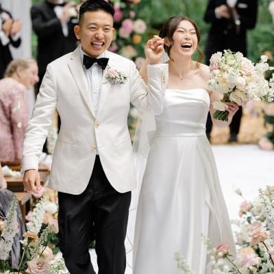Bride and groom hold hands and cheer with joy while walking down aisle after outdoor wedding ceremony at Twin Willow Gardens