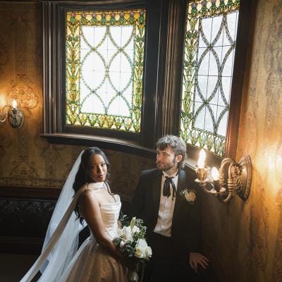 Bride and groom stand together framed by stained glass windows at Joslyn Castle