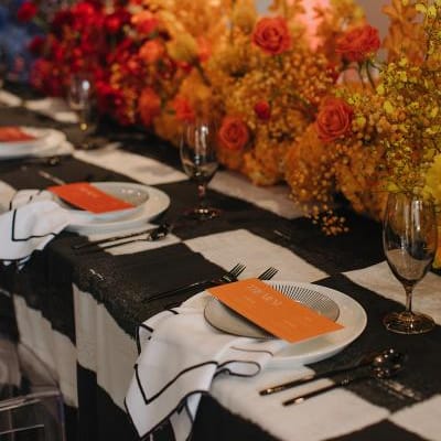 Maximalist tablescape featuring black and white checkered tablecloth and ombre rainbow florals