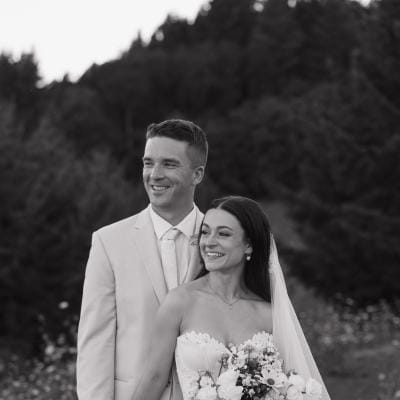Bride and groom stand side by side with scenic views of Youngberg HIll & Winery in the background, black and white