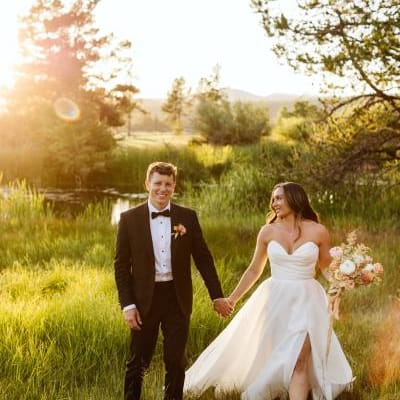 Bride and groom walk hand in hand in the golden hour light on the grounds of Sunriver Resort
